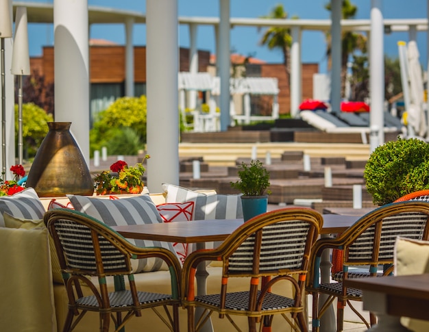 Terrace of a hotel stuffed with soft furnitures in a green space.