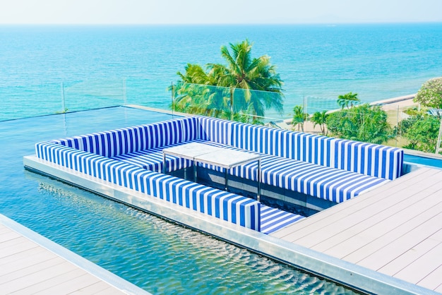 Terrace with blue and white armchairs and a swimming pool around