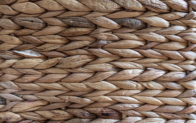 Texture of woven beige straw, background of braids from the plant stem close-up.