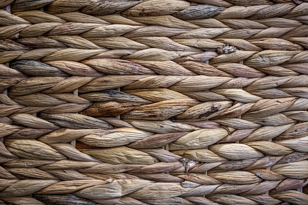 Texture of woven beige straw, background of braids from the plant stem close-up.