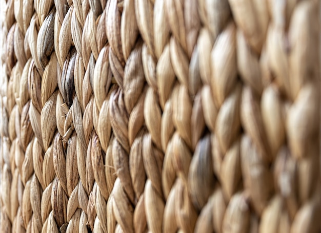 Texture of woven beige straw, background of braids from the plant stem close-up.