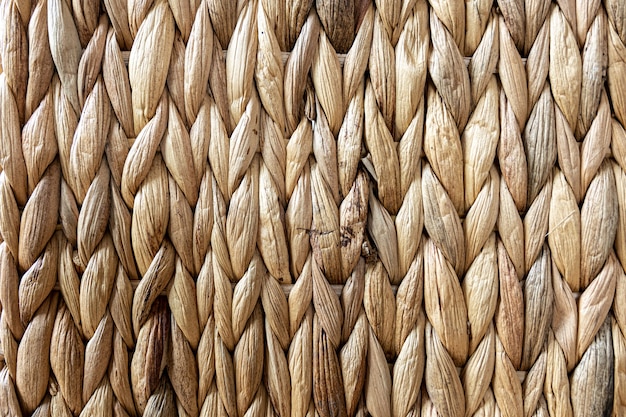 Texture of woven beige straw, background of braids from the plant stem close-up.