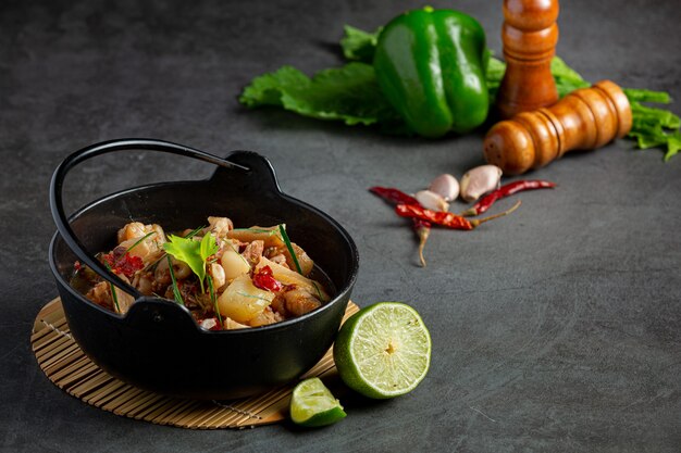 Thai food with spicy pork leg soup in black bowl