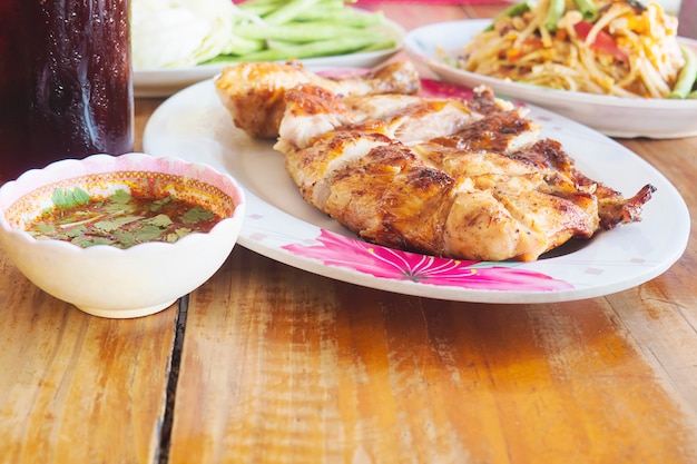 Thai style spicy meal, chicken grilled with spicy papaya salad and cold drink