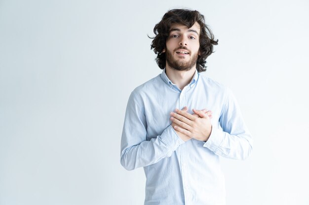 Thankful dark-haired man keeping hands on chest