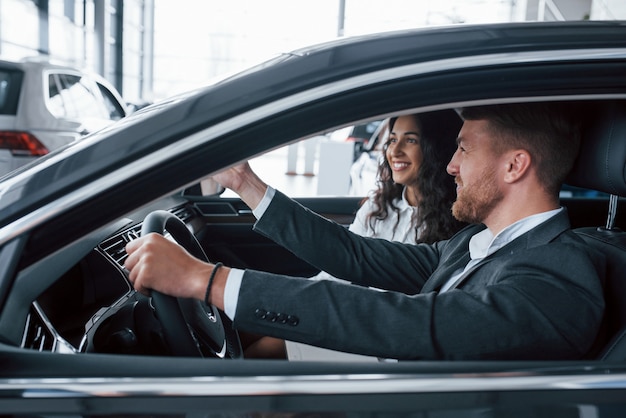 That's looks good. Lovely successful couple trying new car in the automobile salon