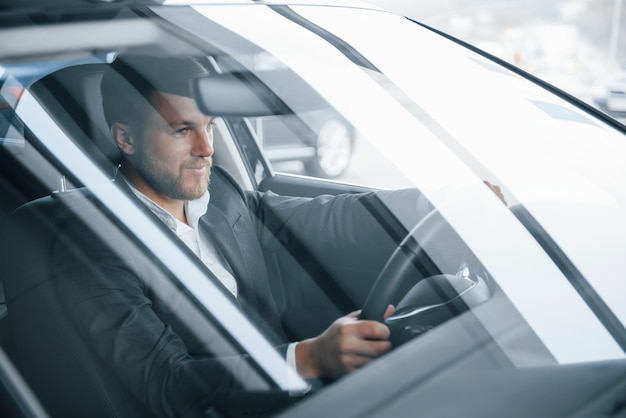 Free Photo that's what success looks like. modern businessman trying his new car in the automobile salon