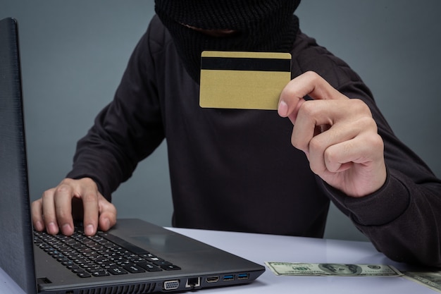 Free Photo thieves hold credit cards using a laptop computer for password hacking activities. 