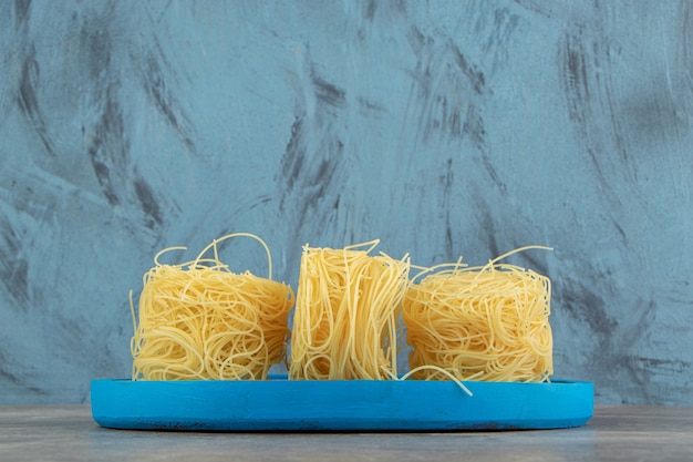 Free photo thin spaghetti nests on blue plate