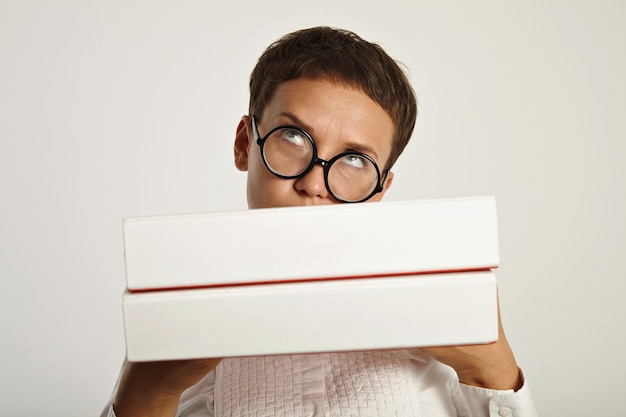 Thinkful brunette wearing round glasses hols big folders in front of her with new educational plan for next year in university