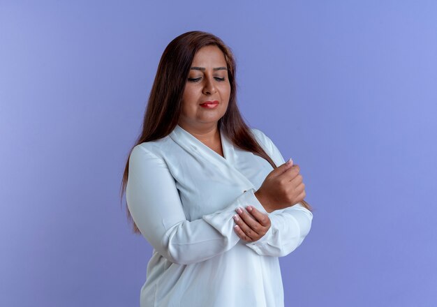 Thinking casual caucasian middle-aged woman grabbed wrist isolated on blue wall