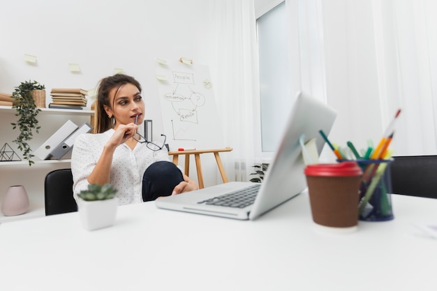 Free photo thinking woman sitting at her office