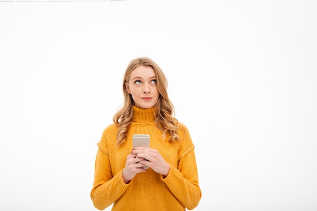 Thinking young woman using mobile phone.