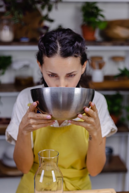 Thirsty woman drinking almond milk from metal bowl in kitchen