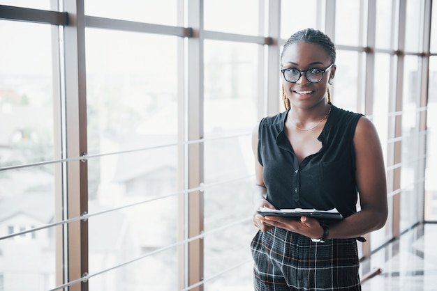 A thoughtful African American business woman wearing glasses holding documents