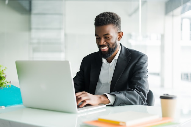 Thoughtful African American businessman using laptop, pondering project, business strategy, puzzled employee executive looking at laptop screen, reading email, making decision at office