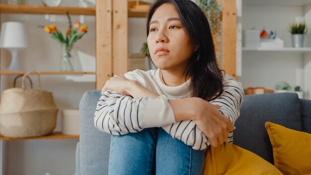 Thoughtful asian lady sit with feel lonely, feeling depressed and spending time alone stay at home