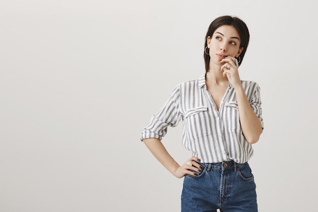 Thoughtful attractive woman looking left at advertisement, thinking or making choice