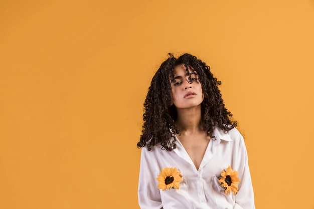 Thoughtful black woman with flowers in shirt pockets