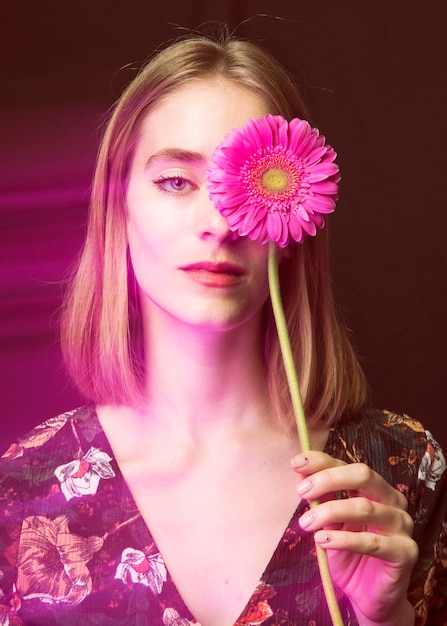 Free photo thoughtful blond woman with pink gerbera