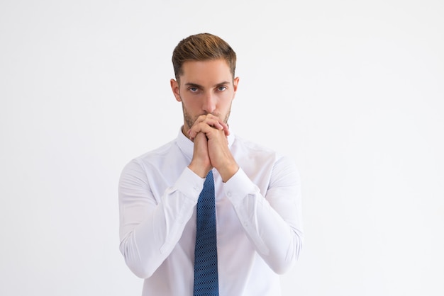 Thoughtful business man touching mouth with clenched hands