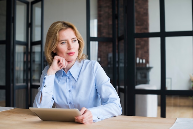 Free photo thoughtful business woman using tablet at table