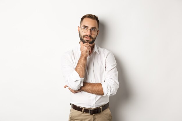 Thoughtful businessman in glasses making plan, looking at upper left corner and thinking, standing