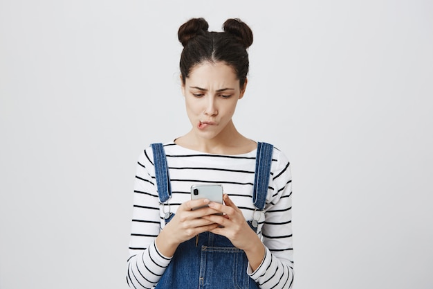 Thoughtful concentrated woman messaging, using mobile phone