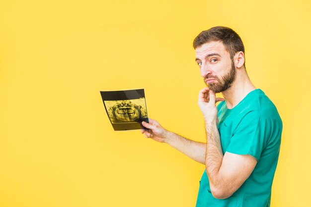 Thoughtful dentist holding teeth x-ray