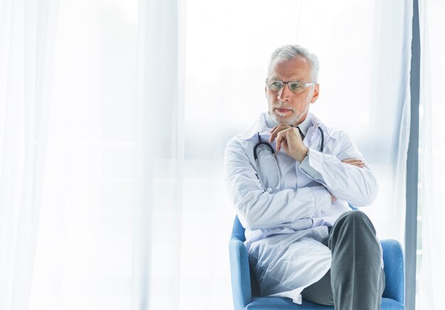 Thoughtful doctor on chair looking away