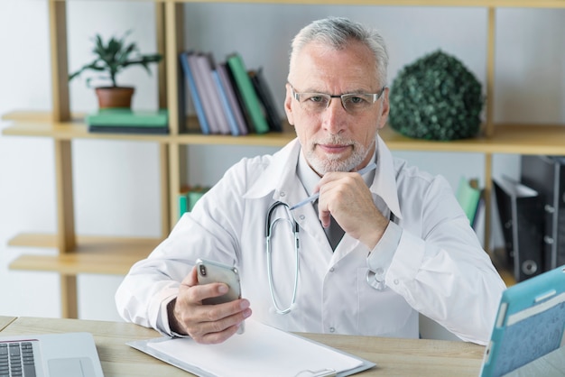 Thoughtful doctor with smartphone