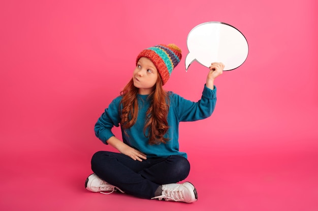 Thoughtful ginger girl looking up and holding bubble speech isolated