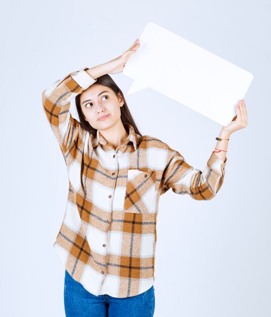  thoughtful girl holding blank speech frame on white wall. 