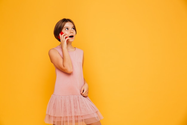 Free Photo thoughtful girl looking up at copy space and talking on smartphone isolated