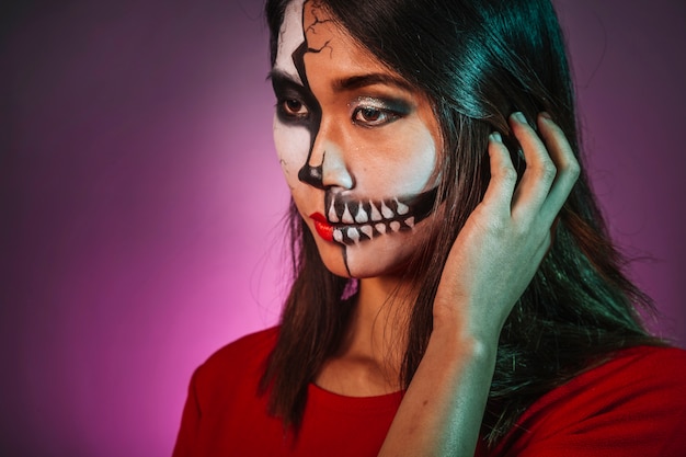 Free photo thoughtful girl with makeup and halloween mask