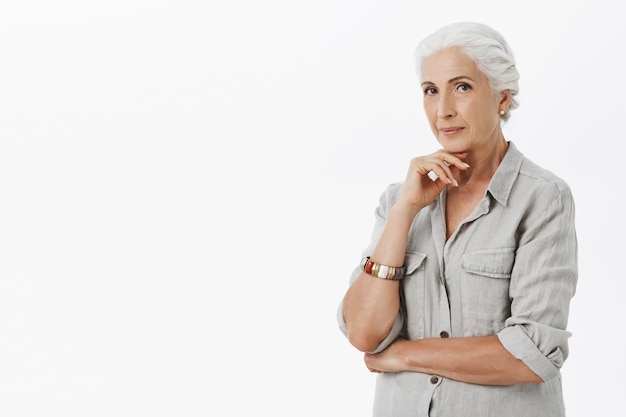 Thoughtful grandmother looking pleased, white background