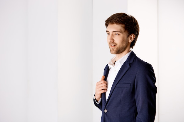 Thoughtful handsome businessman in suit, contemplate view from his business office tower, smiling pleased