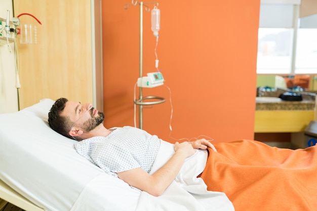 Free photo thoughtful ill patient with oxygen lying on hospital bed during treatment