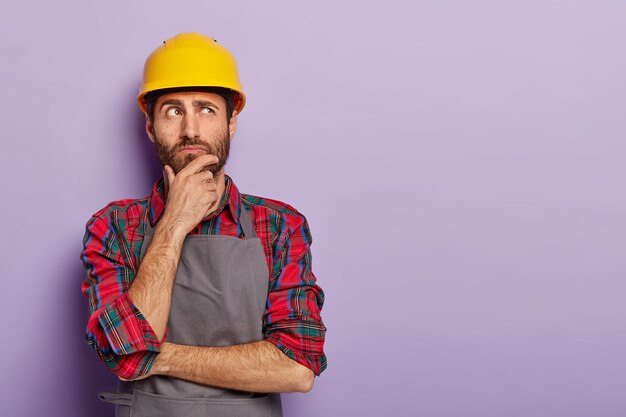 Thoughtful man builder construction touches chin