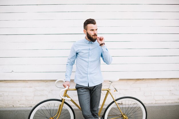 Thoughtful man leaning on bicycle near wall