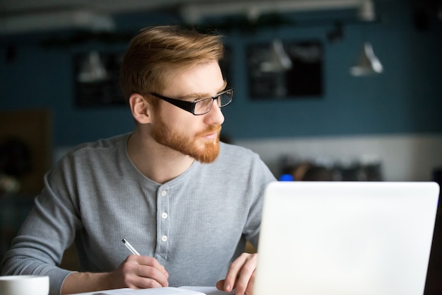 Thoughtful man thinking of new idea writing notes in cafe