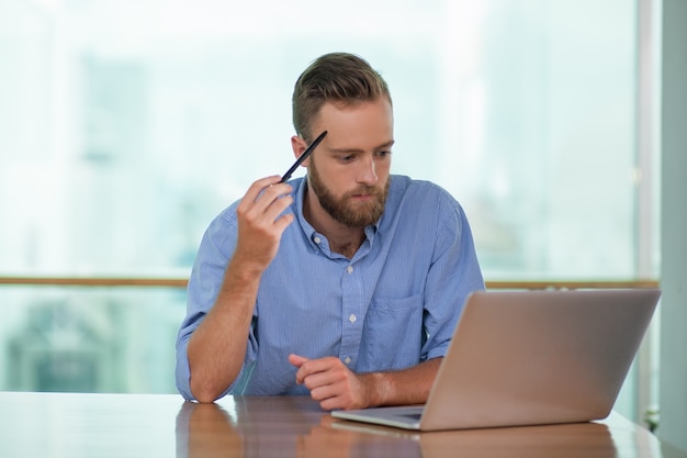 Thoughtful Middle-aged Man Working on Laptop