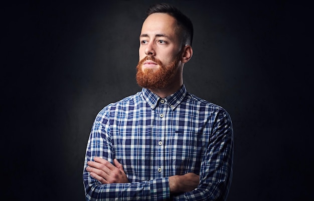 Thoughtful redhead bearded hipster male with crossed arms, dressed in a blue fleece shirt.