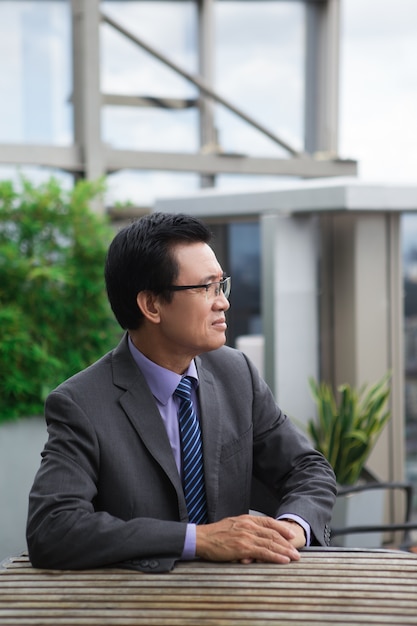 Free photo thoughtful senior businessman at cafe table