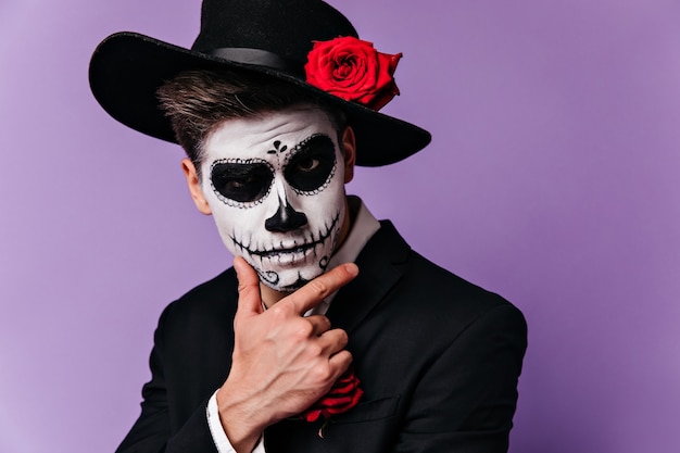 Thoughtful Spanish man in wide-brimmed black hat with serious look posing in suit for Halloween.