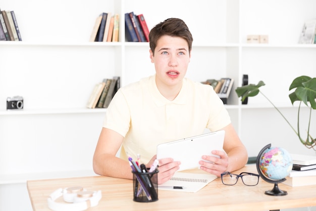 Thoughtful teenager sitting with digital tablet 