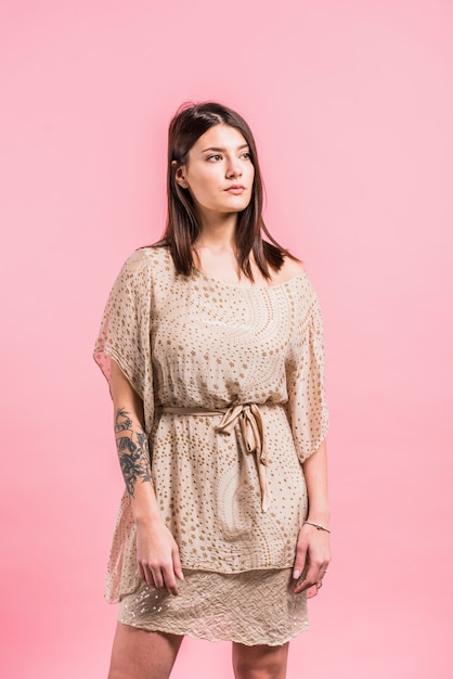 Free photo thoughtful woman in dress on pink background