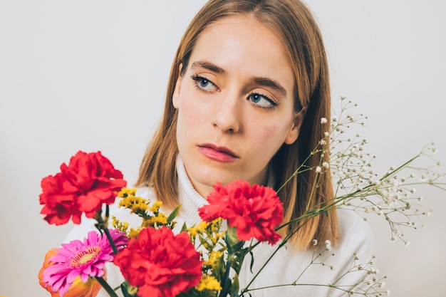 Free photo thoughtful woman holding colorful flowers