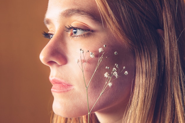 Free Photo thoughtful woman holding small flower at face