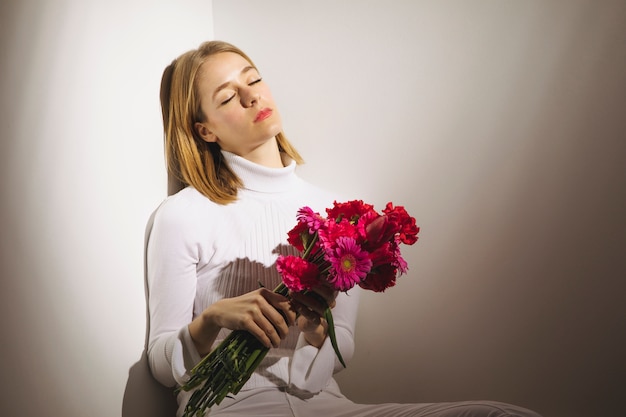 Free photo thoughtful woman sitting with pink flowers bouquet